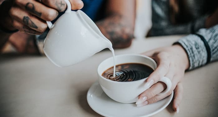 Person Pouring Milk In Tea