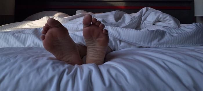 Person's Feet At The End Of Bed