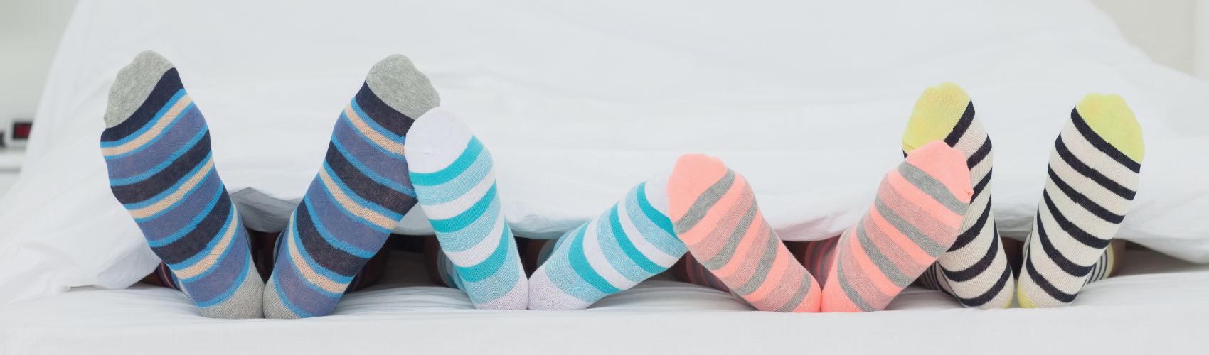 Four people wearing colourful socks in bed