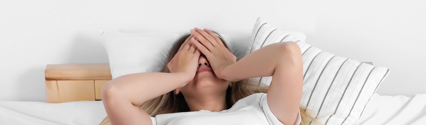 Woman in bed with hands over her face